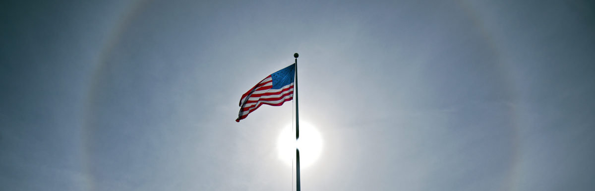 A solar halo illuminates the sky behind an American flag