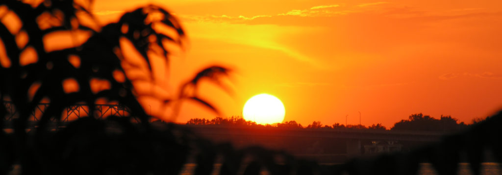 The sun shown on the horizon of a sky with a yellow and orange glow